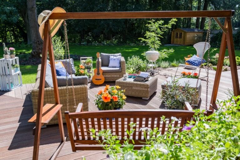Photo of outside patio deck with chairs and tables. There is also a guitar and orange flowers.