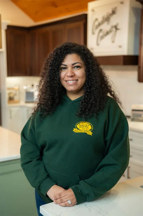 Smiling woman in green sweatshirt in kitchen.